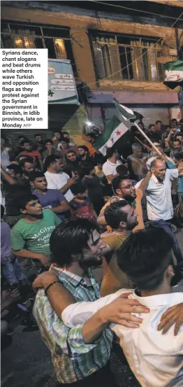  ?? AFP ?? Syrians dance, chant slogans and beat drums while others wave Turkish and opposition flags as they protest against the Syrian government in Binnish, in Idlib province, late on Monday