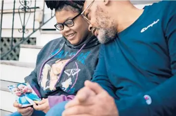  ?? ALYSSA SCHUKAR/THE NEW YORK TIMES ?? Akeerah Jackson, 14, with her father, John, holds a photo of herself with her mother, Cathy Fulcher, who died of COVID-19, at their home in Baltimore on Wednesday.