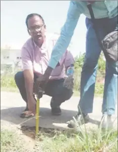  ??  ?? Auditor General Deodat Sharma (stooping) measures the thickness of the №. 52 Cross Street and Middle Walk access South of Public Road.