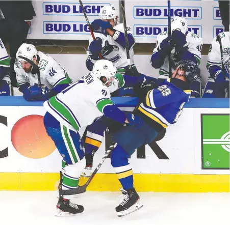  ?? JEFF VINNICK/GETTY IMAGES ?? Canucks forward Zack MacEwen checks St. Louis Blues defenceman Vince Dunn during Game 1 of their Western Conference first-round playoff series at Rogers Place in Edmonton on Wednesday night.
