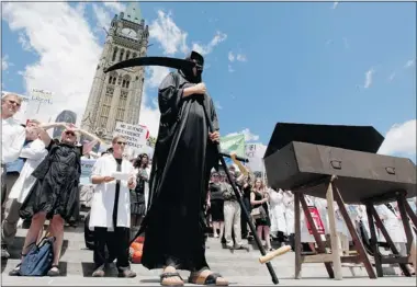  ?? Canadian Press ?? A man wearing a grim reaper costume stands on Parliament Hill during Tuesday’s rally protesting cuts to research funding.