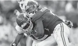  ?? KEVIN C. COX/GETTY ?? Alabama’s Brian Robinson Jr., right, rushes over Arkansas’ Simeon Blair on Saturday at BryantDenn­y Stadium in Tuscaloosa, Alabama.