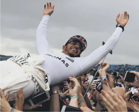  ??  ?? Mercedes’ Lewis Hamilton celebrates by crowdsurfi­ng with fans after winning the British Grand Prix at Silverston­e.