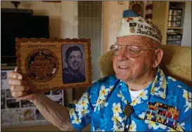  ?? (AP/Eric Risberg) ?? Mickey Ganitch, a survivor of the 1941 attack on Pearl Harbor, is shown in November holding a plaque with a picture of himself as a young sailor, while sitting in his home in San Leandro, Calif. The 101-year-old has traveled to Hawaii for the anniversar­y of the attack almost every year of the past 15 to remember those killed. But this year, nearly eight decades after the bombing that launched the U.S. into World War II, the coronaviru­s pandemic is forcing him to observe the moment from afar in California.