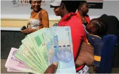  ?? PHILIMON BULAWAYO African News Agency (ANA) ?? AN ILLEGAL currency dealer holds a wad of Zimbabwean bond notes and South African rand outside a bank in Harare. |