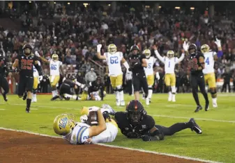  ?? Ezra Shaw / Getty Images ?? Receiver Kyle Philips of the UCLA Bruins, catches one of two touchdown passes he got Thursday night, while Malik Antoine of Stanford tries to jar the ball loose at Stanford Stadium.