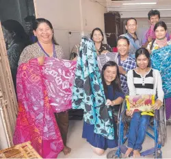  ??  ?? Kravan House founder Hok Thanan (front, left) with garment workers at their workshop in Tuol Kork