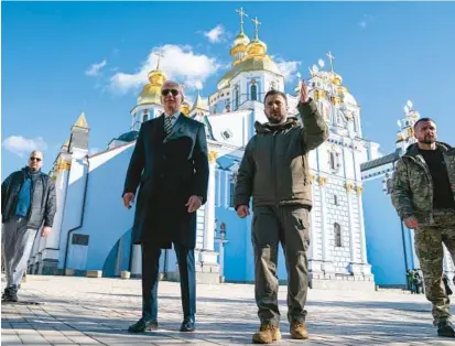  ?? EVAN VUCCI/AP ?? President Joe Biden walks with Ukrainian President Volodymyr Zelenskyy on Monday near a cathedral in a surprise visit to Kyiv.