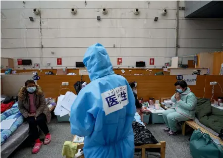  ?? AP ?? A doctor in a protective suit checks coronaviru­s patients at a temporary hospital in a gymnasium in Wuhan in China’s Hubei province, the epicentre of the outbreak. Despite a rise in coronaviru­s cases in countries like South Korea and Italy, China says the daily count of new infections there has fallen.