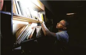  ?? Gustavo Huerta / Staff photograph­er ?? LaDon Johnson searches through old textbooks left behind at the Conroe Normal & Industrial College.