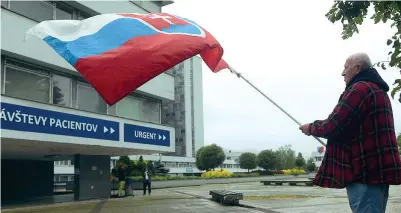  ?? (Afp) ?? Il vessillo
Un cittadino sventola una bandiera slovacca davanti all’ospedale di Banska Bystrica, dov’è ricoverato Robert Fico