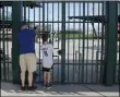  ?? SUE OGROCKI - THE ASSOCIATED PRESS ?? FILE - Cubs fans take photos through the locked gates at Sloan Park, the spring training site of the Chicago Cubs, in Mesa, Ariz., after Major League Baseball suspended the rest of its spring training game schedule because of the coronaviru­s outbreak, in this Friday, March 13, 2020, file photo.