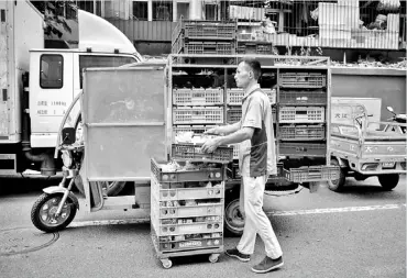  ?? — Gambar AFP ?? HANTAR TEMPAHAN: Seorang pekerja memunggah makanan dari motosikaln­ya untuk dihantar ke pasar raya kecil di sebuah jalan di Beijing, kelmarin.