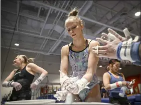  ?? AARON ONTIVEROZ — THE DENVER POST ?? University of Denver gymnast Jessica Hutchinson chalks her hands with teammates during practice at the DU in south Denver on Wednesday.