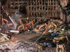  ?? FILE ?? Workers and heavy machinery continue the cleanup and recovery effort in front of the remaining facade of One World Trade Center at ground zero in November 2001. The clearing of the debris took months.