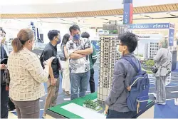  ?? ?? People look at a model of a condo at a housing expo. Total home loans are expected to drop by 4% in 2023 if the LTV measures end.