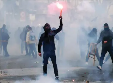  ??  ?? A protester holds a lit flare during clashes with riot police during a demonstrat­ion against the visit of Italian politician Matteo Salvini, in Naples. (AP)