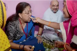  ?? — PTI ?? BJP president Amit Shah with Rajasthan chief minister Vasundhara Raje having lunch with a dalit family in Jaipur on Sunday.