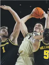  ?? Paul Sancya Associated Press ?? PURDUE’S Zach Edey shoots between Michigan’s Hunter Dickinson, left, and Terrance Williams.