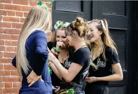  ?? STEPHEN B. MORTON — THE ASSOCIATED PRESS ?? A group of servers from a local hamburger restaurant gather to look at a cell phone photo of themselves in St. Patrick’s Day attire March 17in Savannah, Ga. Last week Savannah’s mayor called off the city’s 196-year-old St. Patrick’s Day parade, but left bars and restaurant­s open for business.