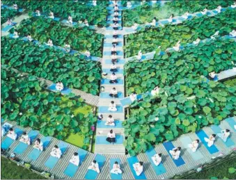  ?? SONG WEIWEI / XINHUA ?? Nearly 1,000 yoga lovers meditate in a field of lotus in Jianning county, Fujian province, on Sunday, during a carnival featuring the flowers. The mountainou­s county has been developing agritouris­m as part of an effort to raise farmers’ incomes.