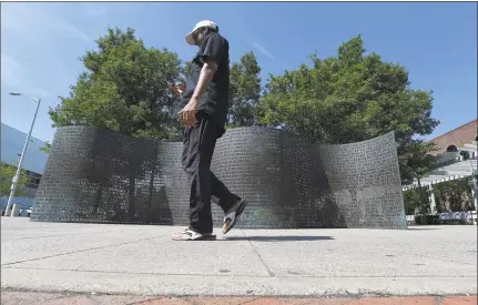  ?? Matthew Brown / Hearst Connecticu­t Media ?? A pedestrian passes a serpentine bronze screen by Jim Sanborn in front of the University of Connecticu­t campus in Stamford on Thursday.