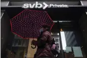  ?? JEFF CHIU — THE ASSOCIATED PRESS ?? A pedestrian carries an umbrella while walking past a Silicon Valley Bank Private branch in San Francisco on March 14.