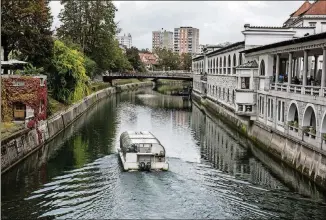  ??  ?? A sightseein­g boat travels along the Ljubljanic­a River in Ljubljana, Slovenia.