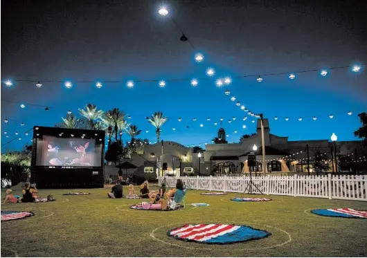  ?? CAITLIN O’HARA/THE NEW YORK TIMES PHOTOS ?? Film viewers sit in socially distant circles July 2 outside the Fairmont Scottsdale Princess hotel in Scottsdale, Arizona.