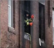  ?? JOE LAMBERTI /CAMDEN COURIER-POST VIA AP ?? A firefighte­r pulls up a hose at the scene of a fatal fire in Philadelph­ia, on Wednesday. Crews responded early morning and saw flames shooting from the second-floor front windows of the home.