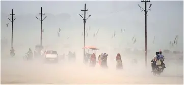  ??  ?? This file photo shows Indian pedestrian­s walking through a dust storm at the Sangam, the confluence of the Ganges, Yamuna and mythical Saraswati rivers in Allahabad. — AFP photo