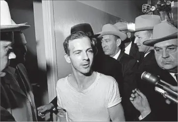  ?? Associated Press ?? LEE HARVEY OSWALD speaks to reporters in a Dallas police station on Nov. 23, 1963 — the day after he killed President Kennedy. One expert complained that the newly released documents are still heavily redacted.