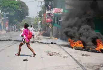  ?? — AFP photo ?? A woman carrying a child runs from the area after gunshots were heard in Port-au-Prince, Haiti.