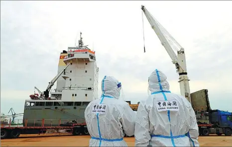  ?? YANG QING / XINHUA ?? Chinese customs officers keep watch after a cargo ship laden with equipment arrives in the Huludao Port, Liaoning province, on Nov 29. The equipment, bound for the Xudapu nuclear power plant, was sent from St. Petersburg in Russia on a three-month journey.