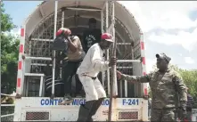  ?? FRAN AFONSO / REUTERS ?? A member of the Dominican Republic security forces stands guard as Haitians jump off a truck on the border between the two countries at the Border Market on Sunday.