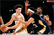  ?? KELVIN KUO ?? Los Angeles Lakers guard Lonzo Ball, left, holds the ball defended by New Orleans Pelicans forward Anthony Davis, front, and guard E'twaun Moore during the second half of an NBA basketball game in Los Angeles, Sunday. The Pelicans won 119-112.