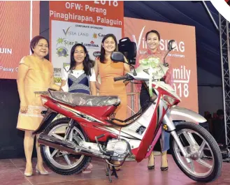  ??  ?? Cynthia Villar, Camille Villar, DOJ Undersecre­tary Emmilene Aglipay-Villar hand the motorcycle prize from Star 8 Green Technology Corp. to raffle draw winner, OFW Anilyne Plata.