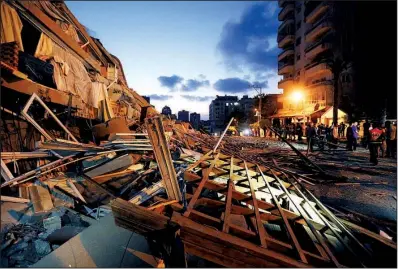  ?? AP/ADEL HANA ?? Palestinia­ns gather Saturday in Gaza City near the rubble of the Zafer Tower apartment building that was leveled by an Israeli strike.