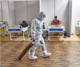  ?? — PTI ?? A doctor drags an oxygen cylinder at CWG village Covid-19 care centre near Akshardham in New Delhi on Tuesday.