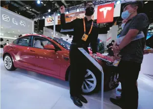  ?? NG HAN GUAN/AP ?? A staff member chats with visitors to the Tesla booth during the China Internatio­nal Fair for Trade in Services on Sept. 1 in Beijing.