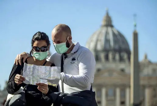  ?? (foto Carconi/Ansa) ?? Via della Conciliazi­one Una coppia di turisti, che indossa le mascherine, guarda una cartina per orientarsi davanti a San Pietro