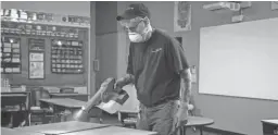  ?? MARK HENLE/THE REPUBLIC ?? Robert Truman, with SSC Services for Education, uses an electrosta­tic sprayer to sanitize a classroom March 12 at Kyrene de la Mirada Elementary School in Chandler.