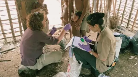  ?? The Invisible Extinction ?? Rutgers University scientist Maria Gloria Dominguez-Bello, left, uses cotton swabs to gather samples from children in the Amazon, as her colleague Monica Contreras records their data.