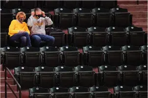  ?? The Associated Press ?? Q A fan puts his mask on after snacking while watching Maryland play Nebraska in the second half of Thursday’s NCAA basketball game in the quarterfin­als of the Big Ten Conference tournament in Indianapol­is. Maryland won 83-73.