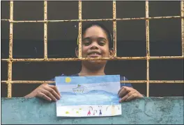  ?? (AP/Ramon Espinosa) ?? Ana Laura Ramirez
Lavandero, 10, holds her drawing May 8 in which she expresses her wish to make a trip to the beach, looking out from the balcony of her home in Havana, Cuba. The only time she’s been able to go out in nearly two months has been for an emergency trip to the dentist. Schools are closed, and because many people in Cuba don’t have internet, the education ministry is broadcasti­ng lessons on state television.