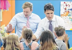  ??  ?? Prime Minister Justin Trudeau, right, and New Brunswick Premier Brian Gallant greet children as they visit Wee College daycare and early learning centre in Moncton, N.B. on Wednesday.