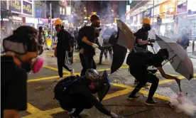  ??  ?? Protesters take cover from teargas canisters. Photograph: Chan Long Hei/EPA