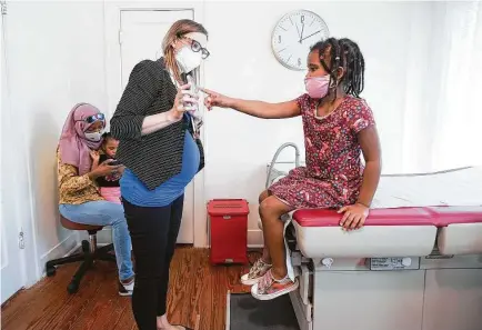  ?? Photos by Elizabeth Conley / Staff photograph­er ?? Dr. Rebecca Berens, with Vida Family Medicine, holds her phone during a checkup for Amatullah Wheeler, 5.