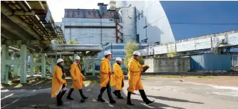  ?? (Gleb Garanich/Reuters) ?? VISITORS WALK past a Safe Confinemen­t arch covering the damaged fourth reactor of the Chernobyl nuclear power plant.