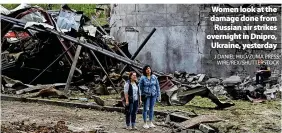  ?? J DANIEL HUD/ZUMA PRESS WIRE/REX/SHUTTERSTO­CK ?? Women look at the damage done from Russian air strikes overnight in Dnipro, Ukraine, yesterday